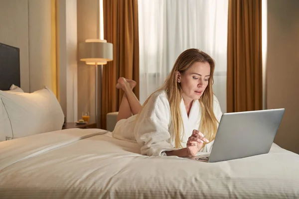 Mujer trabajadora en la cama haciendo clic en portátil — Foto de Stock