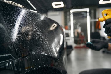 Eldivenli eller, motorlu aracın dış kısmını yağlayıcı maddeyle spreyliyor.