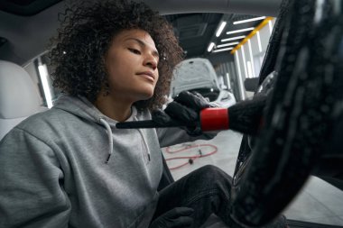 Odaklanmış kadın çalışan, arabanın iç yüzeyini temizliyor.