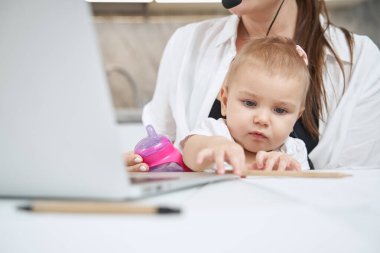 Bebek uzanıyor ve masadan kalem alıyor.