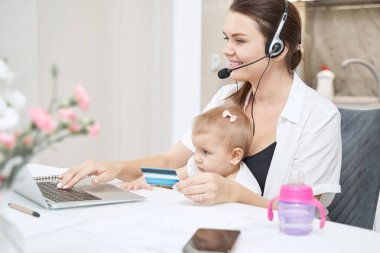 Kadın dizüstü bilgisayarda tuşlara basarken kredi kartını tutuyor