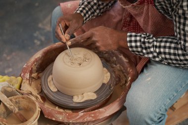 Experienced potter removing excess clay on lower part of bowl clipart
