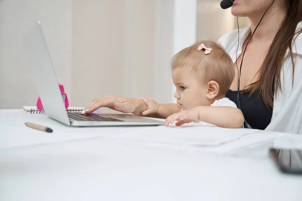 Baby grabbing mother hand while she typing on laptop keyboard — Stock Photo, Image