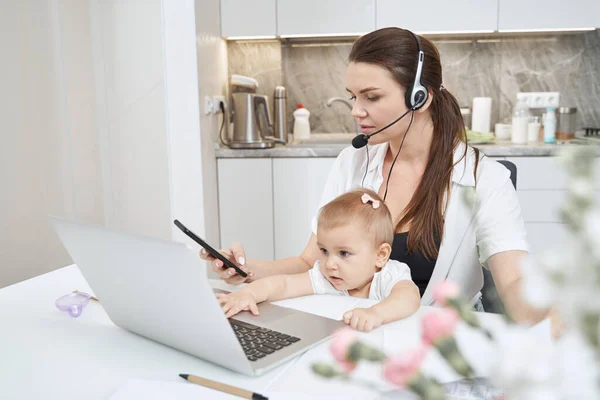 Kvinna klicka på mobilen när du arbetar hemma med barnet — Stockfoto