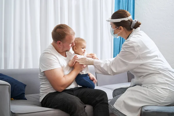 Medico esaminando bambino a casa con il padre — Foto Stock