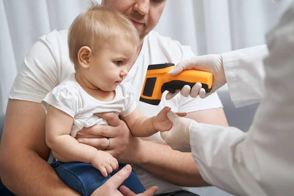 Az orvos infravörös hőmérővel ellenőrzi a baba hőmérsékletét — Stock Fotó