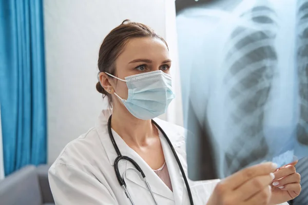 Medico in maschera guardando radiografia petto — Foto Stock