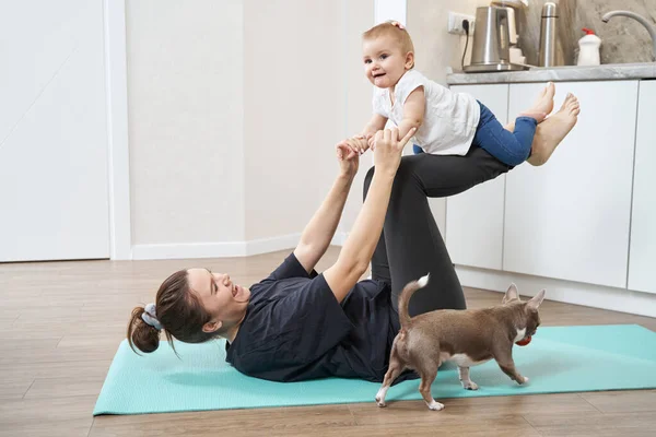 Joyful female lifting kid on her legs during workout — Stock Photo, Image