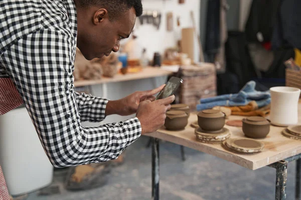 Alfarero masculino concentrado fotografiando sus productos de cerámica —  Fotos de Stock