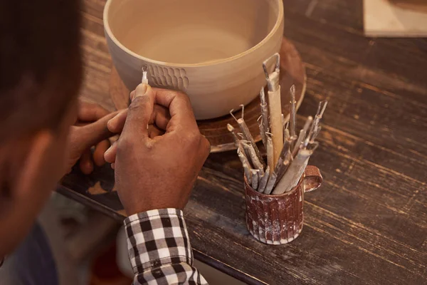 Potter experiente fazendo projetos em faiança com ferramenta cerâmica — Fotografia de Stock