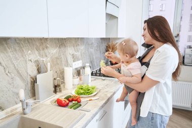 Güzel esmer anne, bebek arabasında bebek kızıyla telefonda konuşuyor.