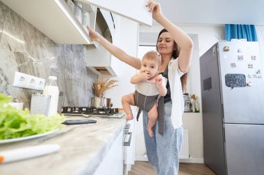 Annesiyle evde vakit geçirirken bebek arabasında oturan tatlı çocuk.