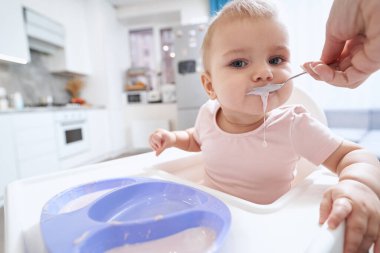 Odadaki fotoğraf makinesine bakarken yüksek sandalyede oturan sevimli küçük kız.