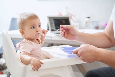 Anne ve babası, bebeği irmik pudingiyle besliyor.