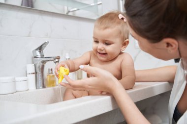 Mutlu gülümseyen bebek banyoda hijyen prosedürü uyguluyor.