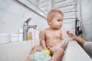 Bebek lavaboda banyo yapıyor. İçerideki odada.