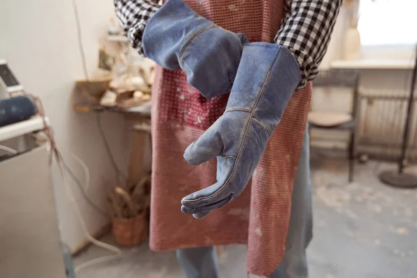 Töpfer zieht Schutzhandschuhe an, bevor er Geräte benutzt — Stockfoto