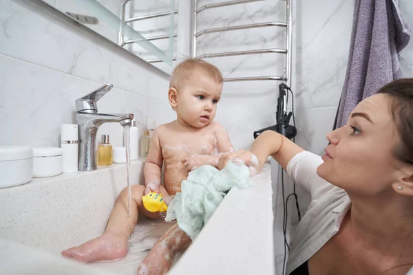 Baby mit Badespielzeug in der Hand verbringt Zeit im Badezimmer während des Hygienevorgangs — Stockfoto