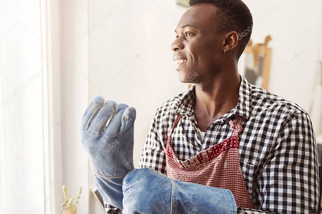 Joyous ceramist putting on his work gloves