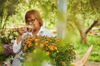 Kırsalda çay içen zarif olgun bir bayan.
