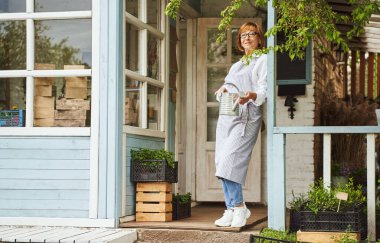Terasta sulama tenekesi olan gülümseyen kadın