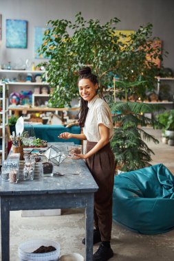 Memnun bayan çiçekçi iş yerinde kameraya poz veriyor.