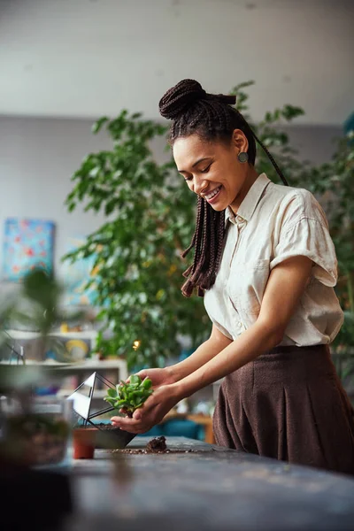 Joyous florist looking at an exotic succulent in her cupped hands — Stock Photo, Image