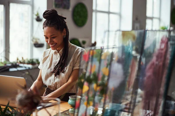 Florista con una sonrisa feliz escribiendo en el portátil — Foto de Stock