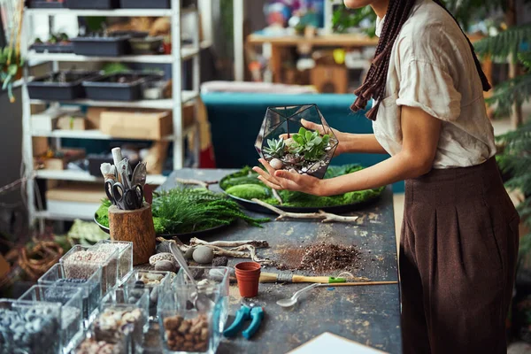 Woman with cornrows holding a polyhedron florarium with both hands — Stock Photo, Image