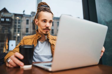 Sokakta defter üzerinde çalışan genç bir hippi.