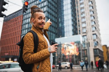 Şehir merkezinde kahve içen neşeli genç adam.