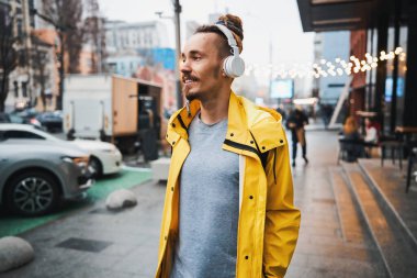 Açık havada yürüyen, çitonlu neşeli genç bir adam.