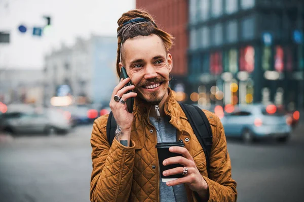 Usmívající se pohledný hipster mluví na smartphone venku — Stock fotografie