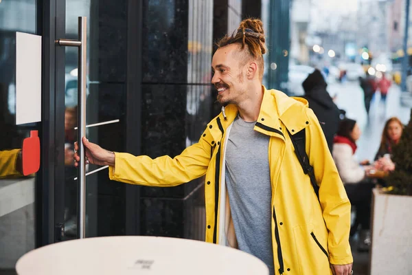 Šťastný mladý muž s dredy vstupující do městské budovy — Stock fotografie