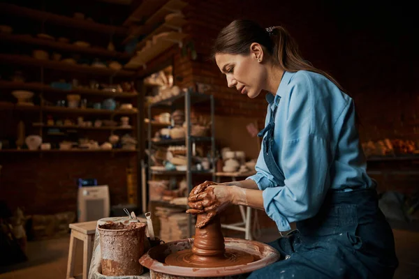 Skupiona brunetka kobieta rzemieślnik modelowanie ceramiczne zastawy stołowe w warsztacie garncarskim — Zdjęcie stockowe