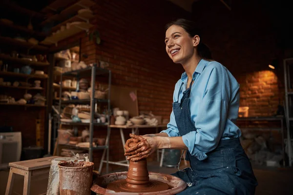 Feliz sonriente bonita ceramista femenina con delantal de trabajo con arcilla húmeda fresca en el estudio de arte —  Fotos de Stock