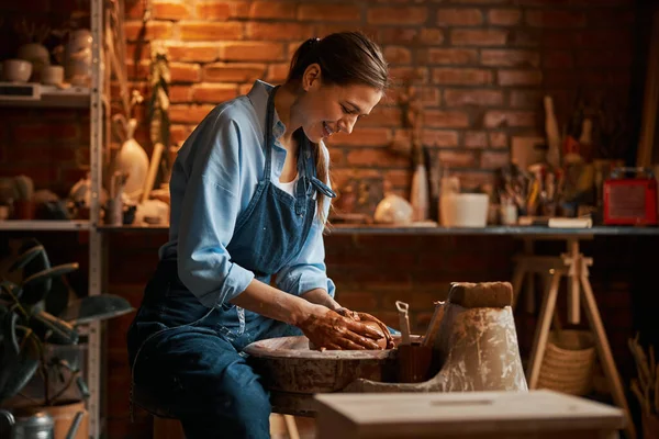 Ceramicista profissional moldando panela de barro na oficina de cerâmica enquanto usa roda de cerâmica — Fotografia de Stock