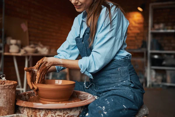 Красивая молодая леди, формирующая глиняную чашу в мастерской — стоковое фото