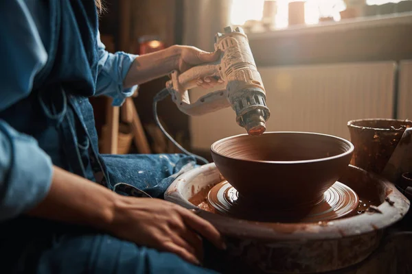 Konzentrierte Bastlerin sitzt auf Töpferscheibe beim Modellieren von Tonschalen im Kunstatelier — Stockfoto