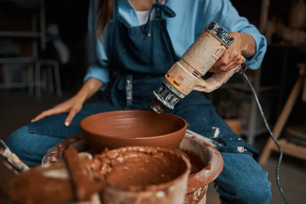 Összpontosított bájos kézműves nő kezében forrasztólámpa a fazekas műhelyben — Stock Fotó