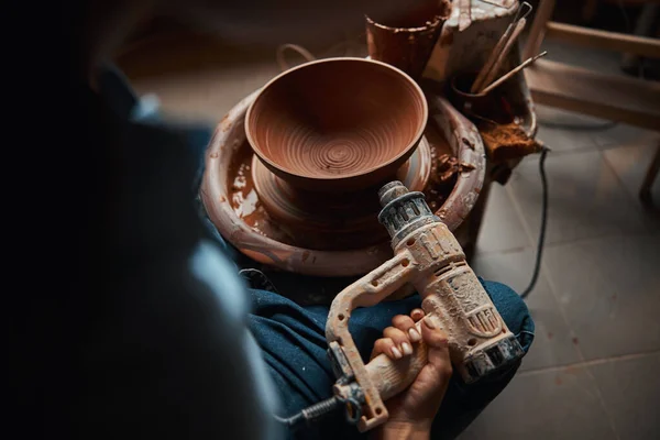 Imagen de mujer artesanal sosteniendo soplete mientras modela vajilla con arcilla húmeda fresca en estudio de arte —  Fotos de Stock