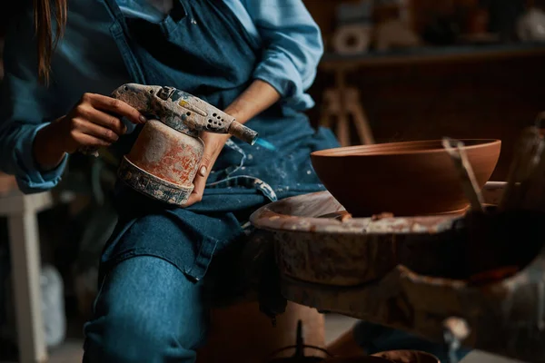 Hermosa mujer artesanal elegante con delantal de trabajo en la rueda de cerámica con arcilla húmeda fresca y herramienta especial en el estudio de arte —  Fotos de Stock