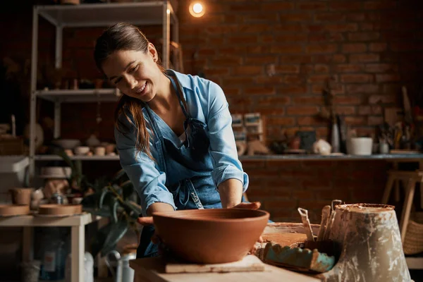 Hermosa atractiva mujer artesanal caucásica sosteniendo cerámica no pintado tazón en la mano en taller de cerámica —  Fotos de Stock