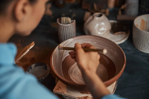Beautiful young craft woman during process manufacturing clay tableware in pottery workshop — Stock Photo, Image
