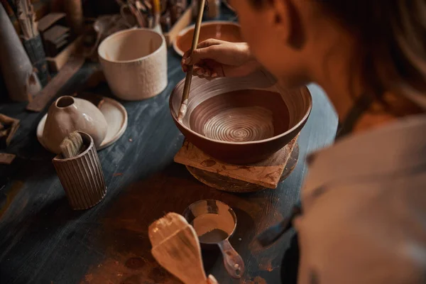 Hermosa mujer artesana elegante durante el proceso de pintura de vajilla de cerámica en taller de cerámica — Foto de Stock