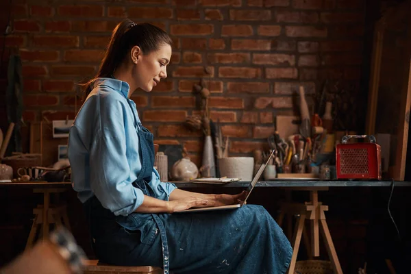Glad leende elegant hantverk kvinna bär uniform tittar på skärmen av bärbar dator — Stockfoto