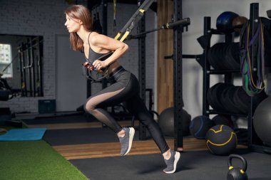 Spor salonunda direniş bantları kullanan sporcu bir kadın.