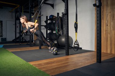 Spor salonunda direniş bantları kullanan atletik bir kadın.