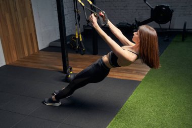 Spor salonunda direniş bantları takan atletik formda bir kadın.