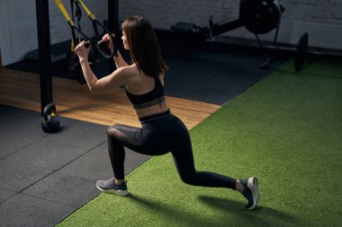 Spor salonundaki spor gruplarıyla hamleler yapan bir kadın.